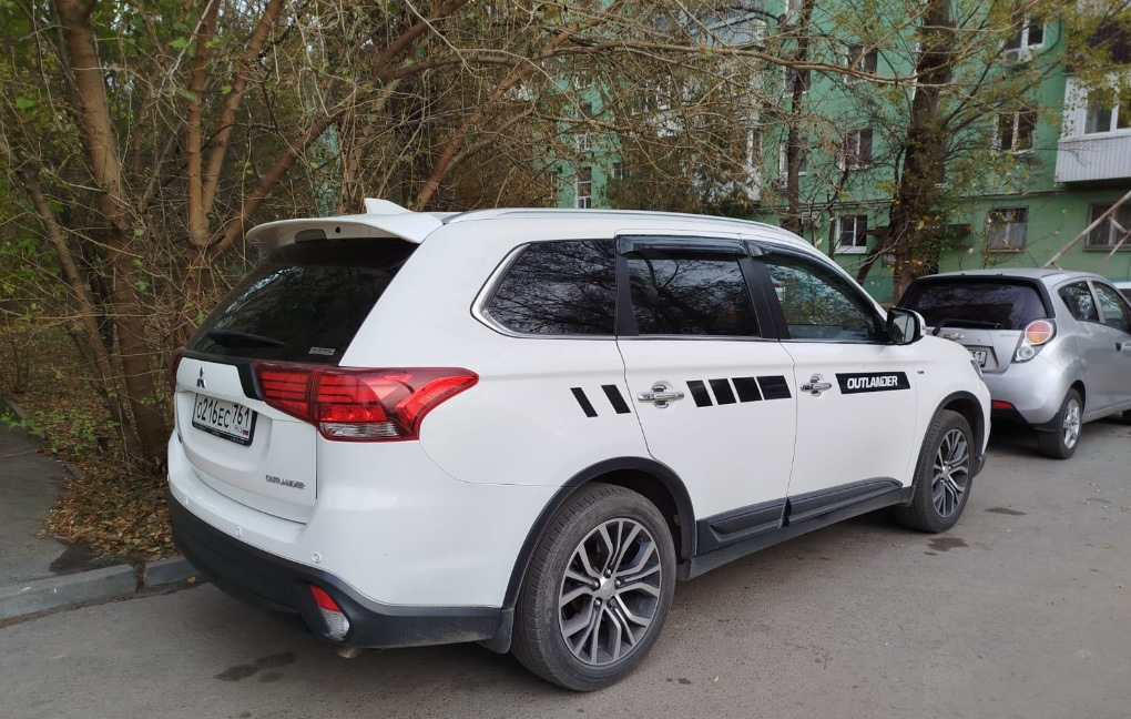 Спойлер — один из немногих элементов стайлинга для Outlander, который вызывает минимум споров — разумеется, с ним лучше, чем без него :)


Со спойлером теперь
Итак, заказал на Али сразу крашеный… По прикидкам некрашеный+покраска (зато точно в цвет) получалась примерно в 15Круб. Окрашеный сразу в белый — 4,3Круб. Решил рискнуть.

Пришел спойлер в транспортную компанию упакованный в пузырчатую пленку основательно, как мумия :)
И, тем не менее — сурпрыз! Заметный залом на внешнем ребре :(


Ну как так?
Ну в той 10-сантиметровой толщины обертке вряд ли так могло получиться, скорее всего сразу таким положили.
В-общем, подал спор (изначально подумал, что оспоренный деньги отдам мастерам, чтобы шпатлевали и красили). Отспорил 1,8Круб. То есть спойлер с дефектом обошелся в 2,5Круб.


По цвету — очень хорошее попадание, разве что на спойлере есть примесь блестящая (наверное, это Polar White или как его там). Но с завода бампера от кузова отличаются существенно сильнее :)
Уже начал у знакомых спрашивать, кто занимается такими работами, никто не признавался… повертел-покрутил в руках и решил кое-что попробовать :)

Сделал технологическое отверстие на внутренней стороне, обмотал изолентой наконечник длинной отвертки, нагрел спойлер в теплой воде, арендовал у жены фен и поставил его на минимальный нагрев.
Ну и изнутри минут за 30 осторожненько выровнял дефект.


Технологическое отверстие и инструмент
Пару недель спойлер отлежался на балконе (проверил, не сработает ли эффект памяти у пластика, когда остынет). Дефект проявился прям минимально (и то, это я знал, куда смотреть). Еще минут 10 повторил процедуру поддавливания и нагрева — и вуаля! Результат отличный.


Живьем вообще место дефекта не найдешь
Следующим квестом оказалось прикрепление.
Дальнейший текст скорее всего будет более интересен ростовчанам…

Беглый поиск стекольного герметика и праймера показал, что это добро обойдется в пару тысяч, не меньше. И потом почти весь герметик все равно на выброс…
Заехал в пару мест, где устанавливают стекла. В одном (федеральная сетка, АвтоТрейд) сразу сказали, что у них нет такой услуги в прайсе, а "внепрайсовые работы" караются штрафом и вплоть до увольнения. Но общались вежливо.

В другом (с довольно живыми социальными сетями, вроде как позиционирующие себя положительно, Автостекла на Вавилова) — просто вышел чувак, ни здрасте, ни досвидания, просто сказал "нет, я это делать не буду" и развернулся. Резкий контраст с социальными сетями. Неприятный осадочек :)

Уже подумал — ну всё, придется самому материалы покупать и звать кого-нибудь на помощь для ровной установки. Но решил заглянуть к еще одним установщикам автостекол. Оказалось, неподалеку есть AG Experts. Ребята красавчики — и пообщались вежливо, и один парень вышел посмотрел-пощупал спойлер. Согласились сделать. Подошли прям очень профессионально — все обезжирили, нанесли праймер, погрели феном и спойлер и крышку багажника, нанесли герметик, приклеили спойлер. И стоимость услуги нормальная — 1,5Круб.


Кепка
В-общем, теперь Белый Бумбр со спойлером.
Считаю, что он делает внешний вид аута существенно гармоничнее. Плюс стоимость доработки получилась ну очень приятной.