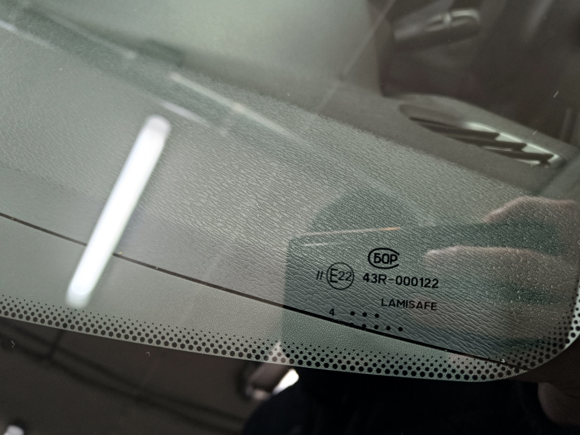 В общем, машина стояла на улице весь ноябрь. Приехал с командировки и утром завёл, а сам пошел домой пить чай пока она грелась. Через пол часа выхожу и вижу, что по всей длине лобовой появилась трещина от небольшого скола — поймал камушек летом, когда ехал на море.

Трещина на всю длину. Стекло SISECAM
Вроде особо и не мешается, но напрягало, что находится на уровне глаз. Так покатался где-то месяц и решил позвонить нескольким фирмам, так сказать узнать цены рынка. Первой фирмой оказалась AG Experts. Цену за стандартное стекло Бор с небольшим затемнением и зелёным оттенком озвучили 7800 рублей. Установка бесплатная. После этого даже звонить не стал другим фирмам, а сразу записался на удобную дату — цена меня устроила. Во время разговора уточнил ещё раз нужную модель стекла с евро-кодом 4592AGS и переспросил точно будет оригинальный Бор, а не какой-то кооператив… Ответили, что будет 100% Бор, который сейчас ставят на конвейер, надо только выбрать вариант его исполнения: с датчиками или без, и т.п. Попросили в день установки заранее заехать на мойку.

А вот и мойка. Прайс — космос для Уфы, одна фаза 600 рублей 🙂 и это только наружка…
После мойки заехал в соседний бокс, где уже весёлые ребята за несколько минут разобрали жабо и сняли старое лобовое.

Старое заводское стекло SISECAM
На фото видно тот самый скол, с которого всё пошло по швам…

Парни срезали лишний герметик и обезжирили поверхность
Видно, что на заводе особо не заморачиваются и наносят герметик так себе. Теперь понятно, почему у некоторых владельцев вода в салоне: на фото можно найти уязвимые места.

Новое стекло установлено. Теперь у нас Бор.
Пол часа и готово!

Стекло ветровое Бор 8450007323 E22 43R-000122 Lamisafe
После того как приклеили, я ещё часик погулял в ближайшем ТЦ пока схватится герметик, вернулся и успел пообщаться с мастерами. Прошло 2 часа и я не спеша поехал домой.

P.s. Парни сказали, что стекла AGS и Бор делают в одном заводе, чему я был удивлён.